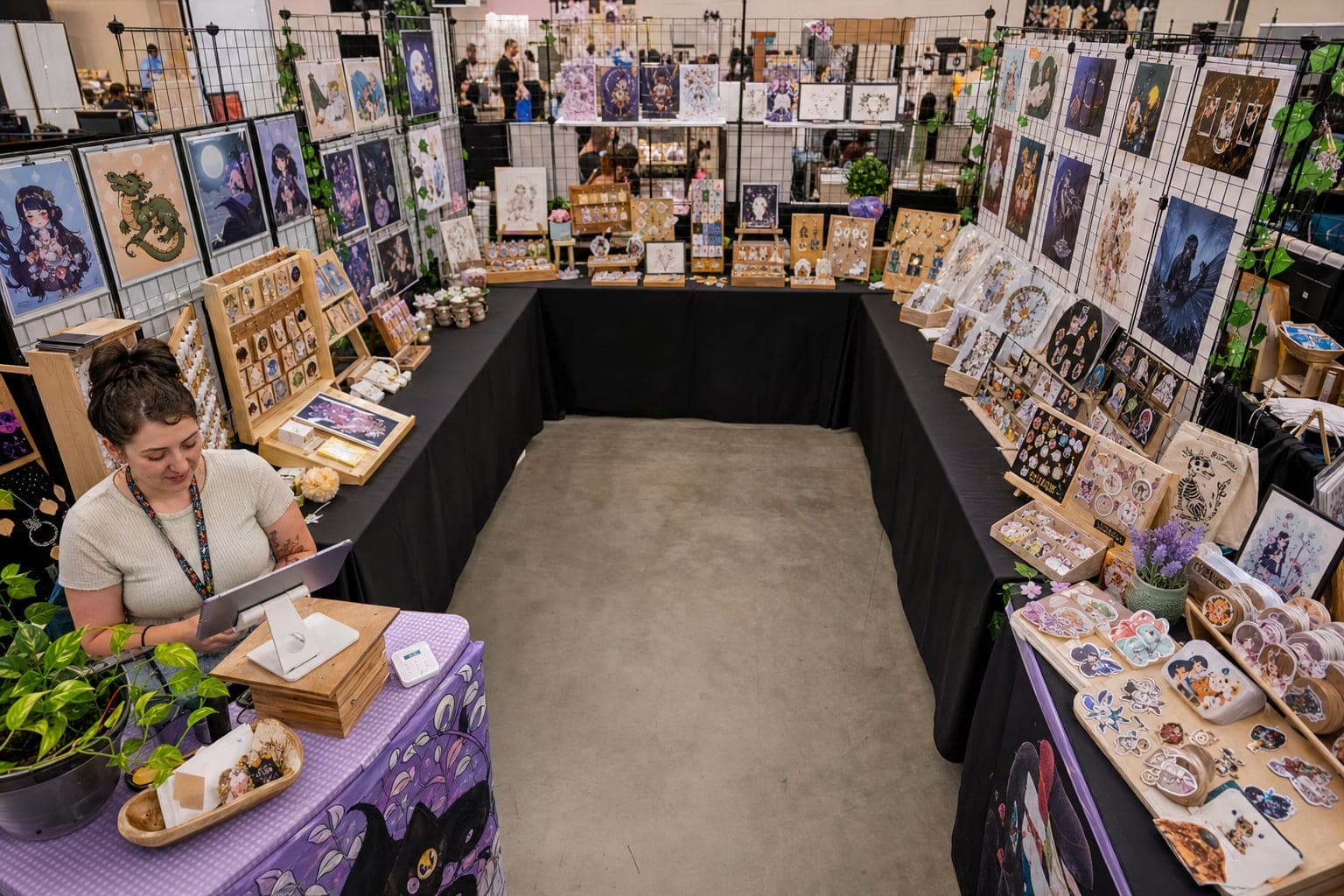 Overhead view of a 10x10 craft show booth arranged in a U-shape with side and back display tables, an open front entry, and a checkout counter in the near corner